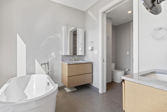 full bath featuring vanity, toilet, baseboards, a freestanding bath, and tile patterned floors