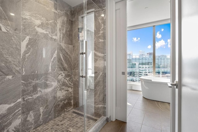 full bathroom with tile patterned flooring, a view of city, a stall shower, and a soaking tub
