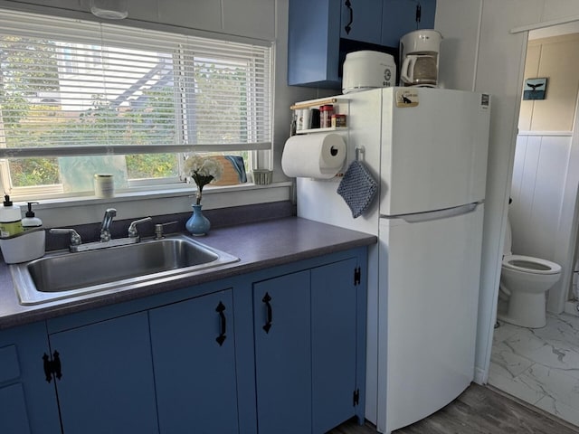 kitchen featuring white refrigerator, plenty of natural light, sink, and blue cabinetry