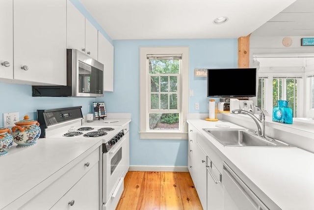 kitchen featuring sink, a wealth of natural light, white cabinets, and white appliances