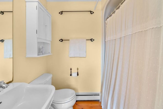 bathroom with wood-type flooring, sink, baseboard heating, and toilet