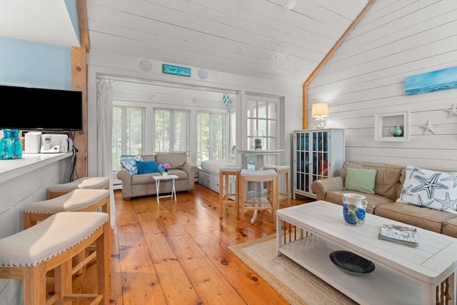 living room featuring vaulted ceiling, wooden walls, wood ceiling, and light hardwood / wood-style floors