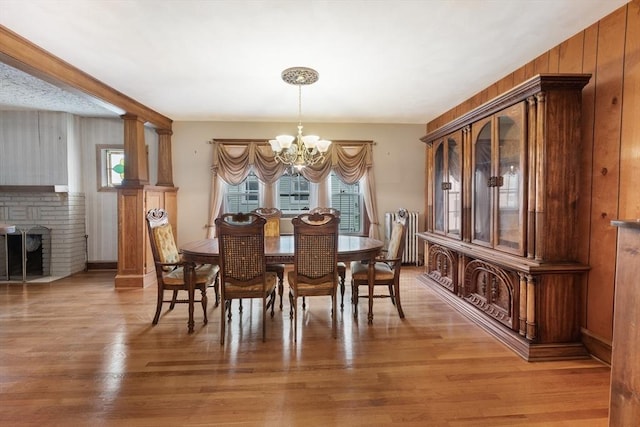 73 Biltmore St, Springfield, MA 01108 - dining space with a chandelier, light wood finished floors, a fireplace, and wooden walls