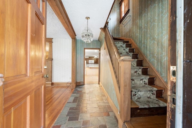 73 Biltmore St, Springfield, MA 01108 - stairway featuring a chandelier, stone tile flooring, beamed ceiling, and wallpapered walls
