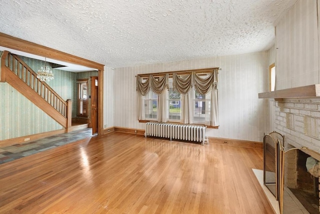 73 Biltmore St, Springfield, MA 01108 - unfurnished living room with radiator, wood finished floors, a textured ceiling, stairs, and a chandelier