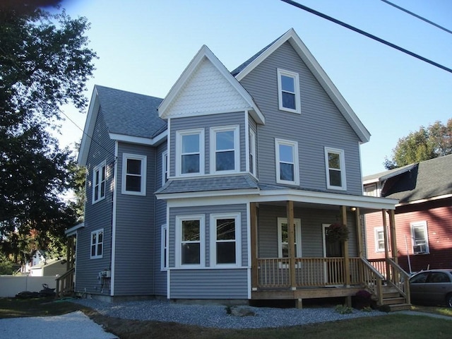 view of front facade featuring covered porch and a shingled roof