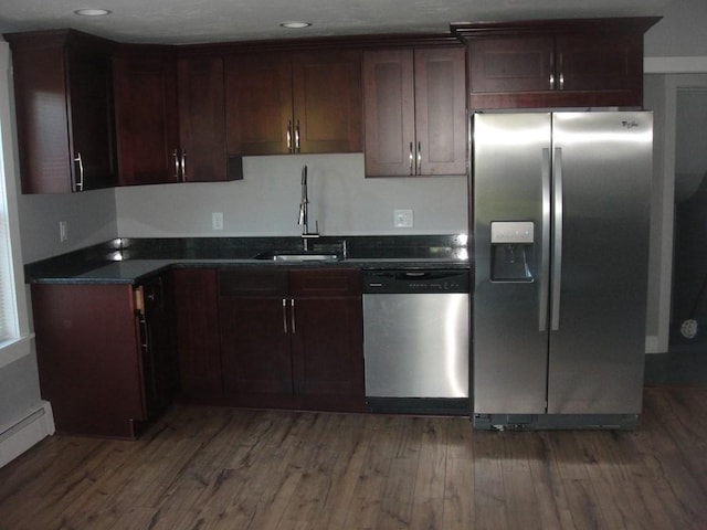 kitchen featuring a sink, dark countertops, stainless steel appliances, light wood finished floors, and a baseboard radiator