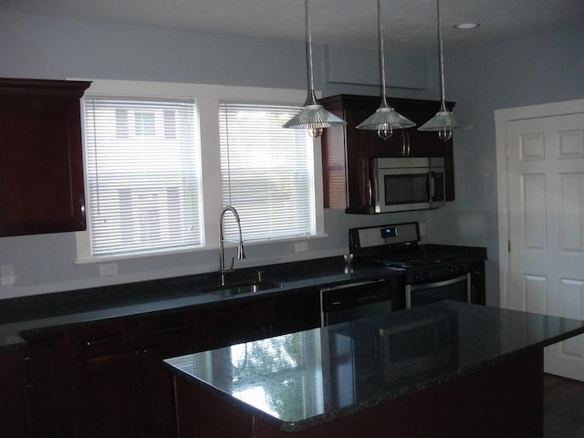 kitchen featuring a kitchen island, pendant lighting, dark stone countertops, appliances with stainless steel finishes, and a sink