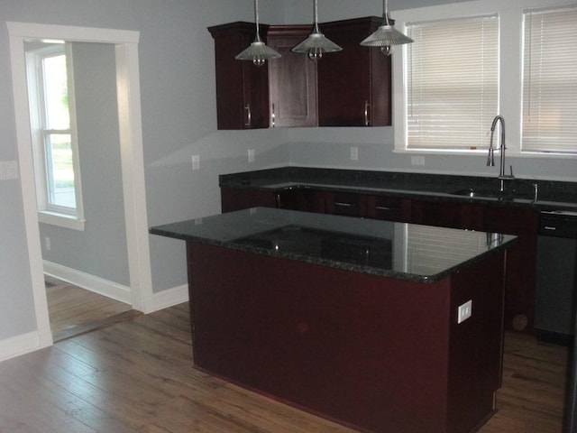 kitchen featuring a center island, baseboards, dark wood finished floors, decorative light fixtures, and a sink