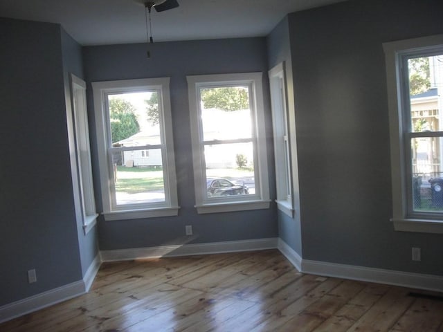 empty room featuring baseboards, a healthy amount of sunlight, and hardwood / wood-style floors