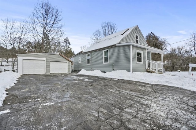 view of snowy exterior featuring a garage and an outbuilding