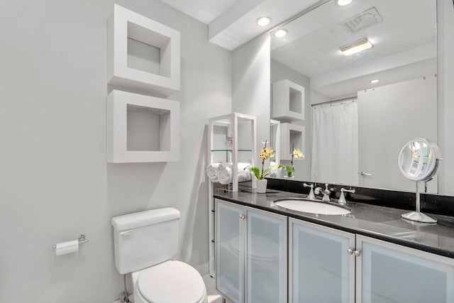 bathroom featuring a shower with shower curtain, vanity, and toilet