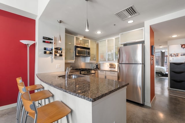 kitchen with kitchen peninsula, a kitchen breakfast bar, stainless steel appliances, sink, and hanging light fixtures