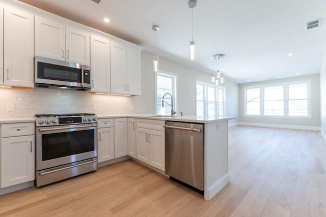 103-105 Neponset Ave, Boston, MA 02131 - kitchen featuring stainless steel appliances, a peninsula, light countertops, light wood-type flooring, and tasteful backsplash