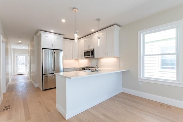 103-105 Neponset Ave, Boston, MA 02131 - kitchen featuring stainless steel appliances, a peninsula, light wood-type flooring, light countertops, and white cabinetry