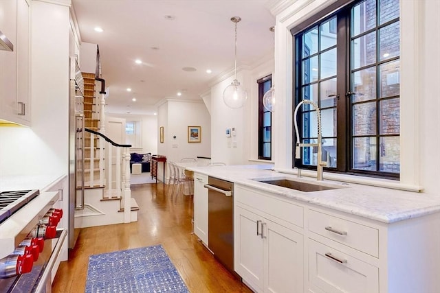 kitchen with appliances with stainless steel finishes, white cabinetry, light stone counters, and hanging light fixtures