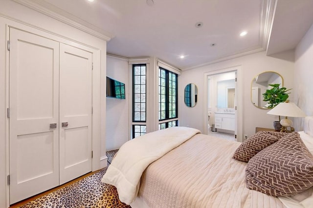 bedroom featuring light hardwood / wood-style floors, ornamental molding, and ensuite bath