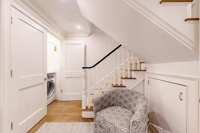 clothes washing area featuring light hardwood / wood-style floors, crown molding, and washer / clothes dryer