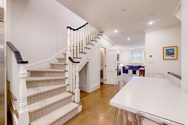 stairway with hardwood / wood-style floors and ornamental molding