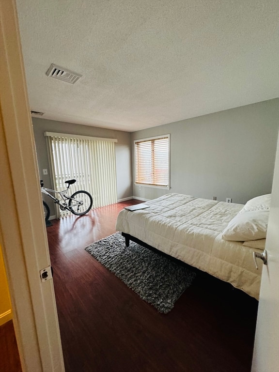 bedroom featuring a textured ceiling and dark hardwood / wood-style flooring