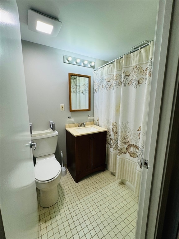 bathroom with toilet, tile patterned flooring, vanity, and walk in shower