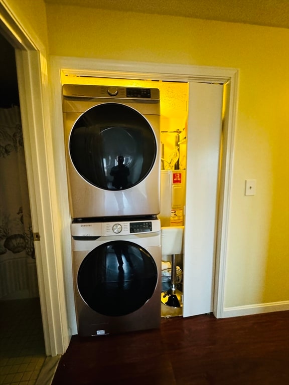 washroom featuring hardwood / wood-style floors, stacked washer / dryer, and water heater