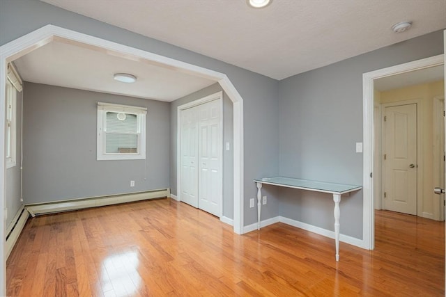 48 Rosemont St Unit 48, Haverhill, MA 01830 - empty room with a smoke detector, wood finished floors, arched walkways, and a baseboard heating unit