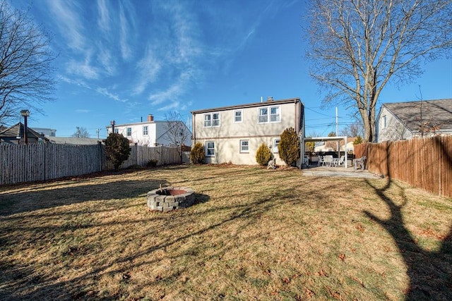 back of property featuring a fire pit, a patio area, and a lawn