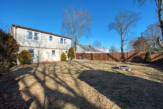 back of house with a yard and an outdoor fire pit