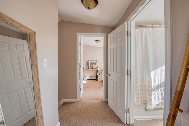 corridor with light colored carpet and vaulted ceiling