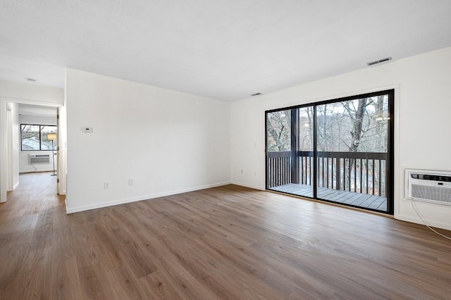 empty room with an AC wall unit and dark wood-type flooring