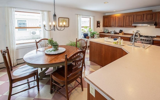 kitchen featuring sink, a notable chandelier, pendant lighting, a center island with sink, and stainless steel stove