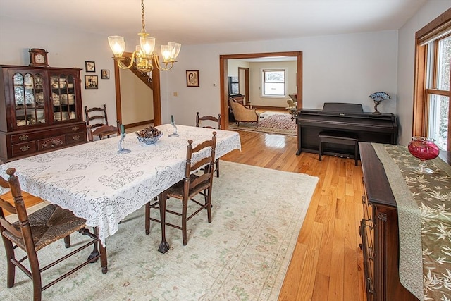 dining room featuring a healthy amount of sunlight, light hardwood / wood-style flooring, and a notable chandelier