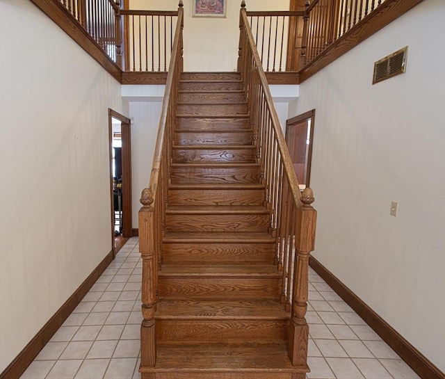 stairs with tile patterned floors and a towering ceiling