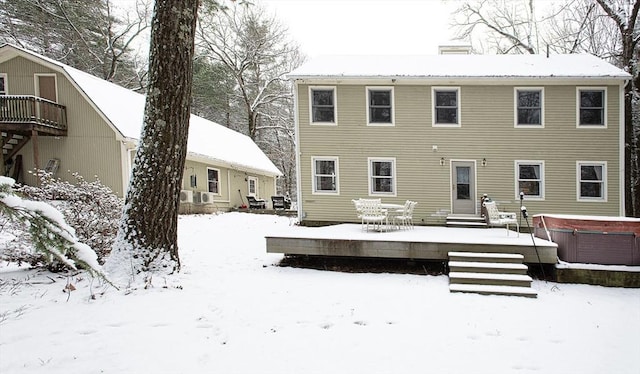 snow covered back of property featuring a hot tub