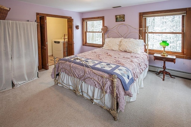 bedroom featuring multiple windows, light carpet, separate washer and dryer, and a baseboard heating unit