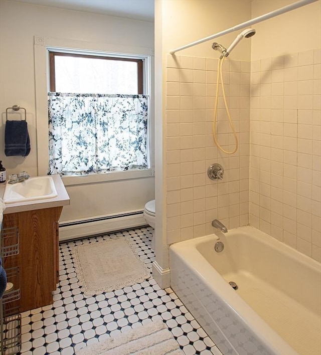 full bathroom with vanity, a baseboard radiator, toilet, and tiled shower / bath