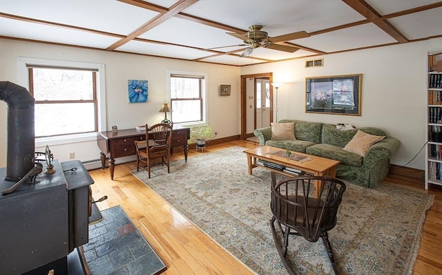 living room with hardwood / wood-style floors, ceiling fan, a wood stove, and coffered ceiling