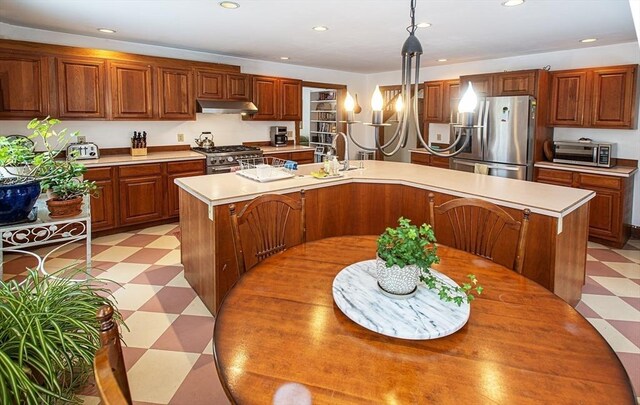 kitchen with a center island with sink, stainless steel appliances, and hanging light fixtures