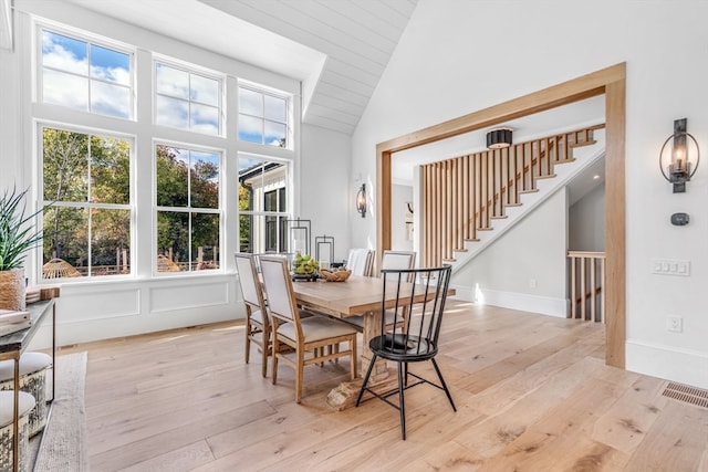 dining area featuring high vaulted ceiling, a wealth of natural light, and light hardwood / wood-style flooring