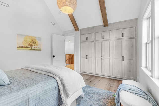 bedroom with beamed ceiling, light wood-type flooring, a closet, and high vaulted ceiling