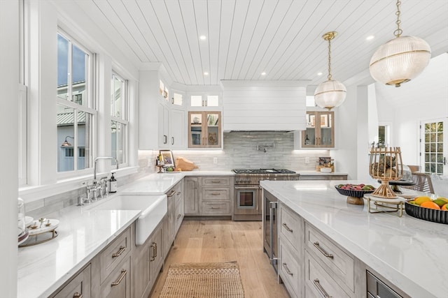 kitchen featuring hanging light fixtures, sink, a wealth of natural light, and light stone counters