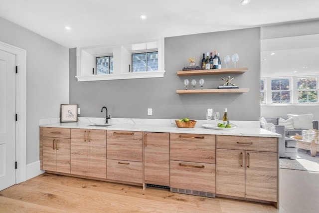 interior space featuring light stone countertops, light hardwood / wood-style flooring, sink, and a healthy amount of sunlight