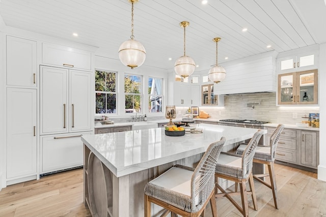 kitchen with pendant lighting, light wood-type flooring, white cabinets, and a spacious island