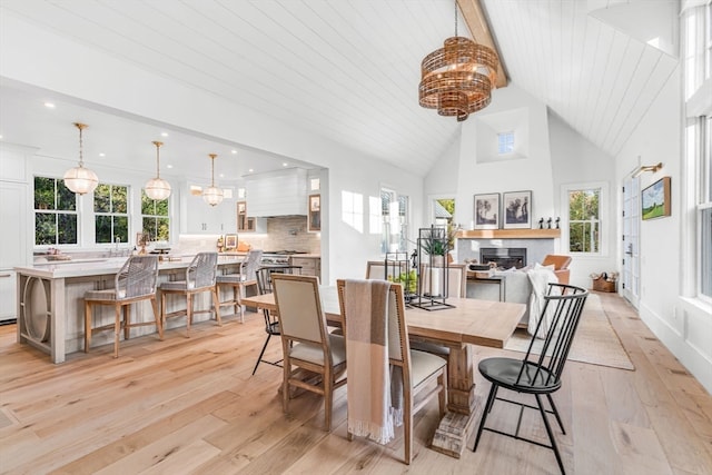 dining room featuring wood ceiling, light hardwood / wood-style floors, high vaulted ceiling, and a healthy amount of sunlight