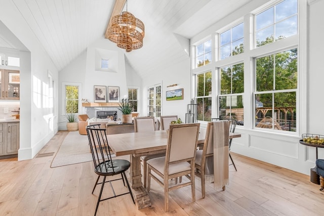 dining room with high vaulted ceiling and light hardwood / wood-style floors