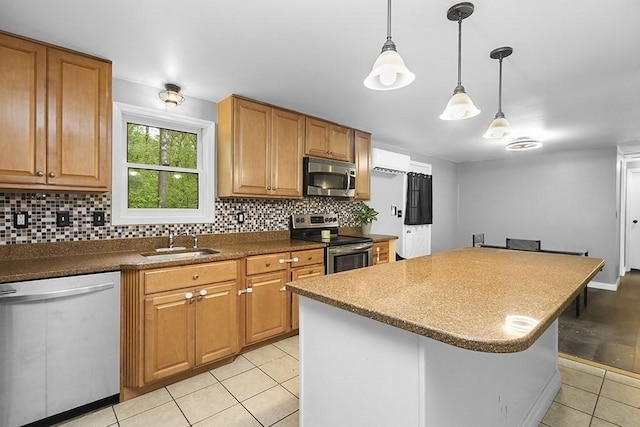 kitchen with appliances with stainless steel finishes, a sink, light tile patterned floors, tasteful backsplash, and a kitchen island