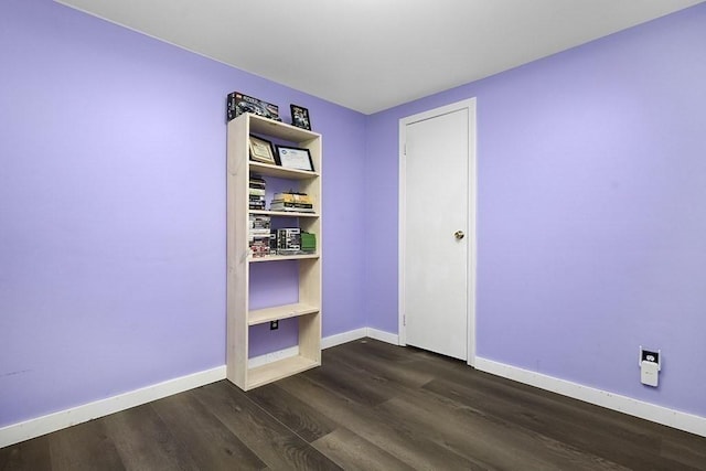 spare room with dark wood-type flooring and baseboards