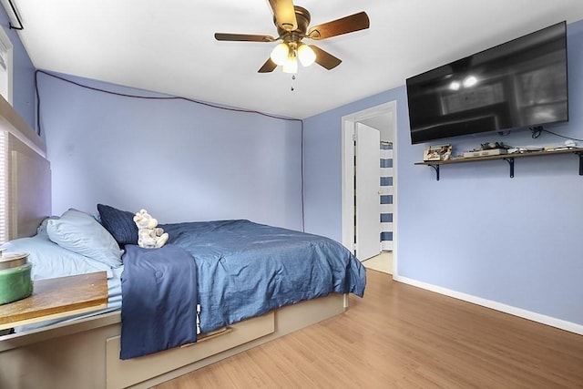 bedroom featuring baseboards, wood finished floors, and a ceiling fan
