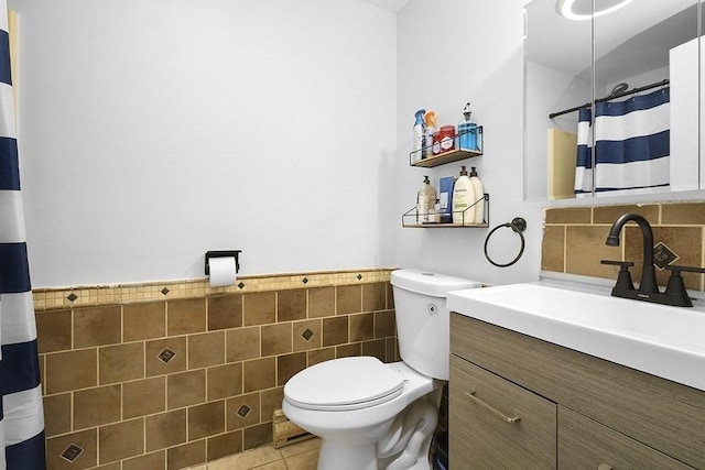 full bathroom featuring tile walls, toilet, wainscoting, vanity, and tile patterned flooring